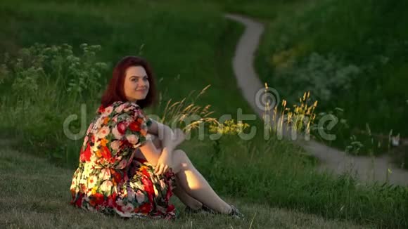 快乐的年轻女子坐在公园的草地上静态射击视频的预览图