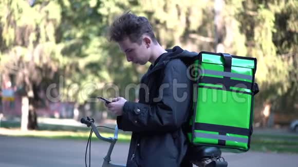 送货的人带着绿色的背包和自行车正在寻找客户电话地址视频的预览图