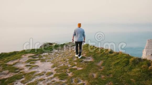 后景青年游客走在危险的道路上诺曼底海岸悬崖欣赏史诗般的海景视频的预览图