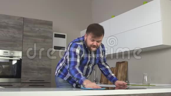 一个长着胡子的开朗肥胖的白种人在现代化的厨房里洗了一张桌子动作慢干净视频的预览图