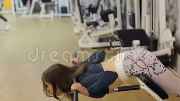 运动的年轻女人在健身房里做着过度伸展运动视频的预览图