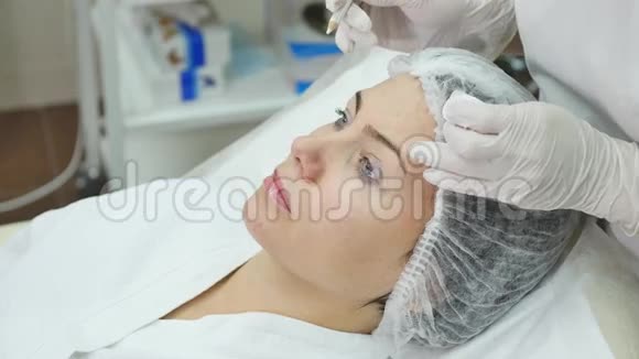医生在病人脸上用记号笔画出线用于诊所的面部整形手术视频的预览图