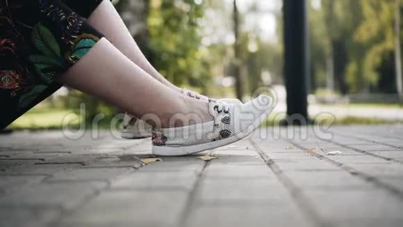 那个女孩正轻松地坐在公园的长凳上把她的腿收起来好天气视频的预览图