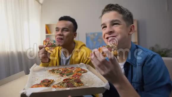 非裔美国人和白人青少年享受披萨和看喜剧表演视频的预览图