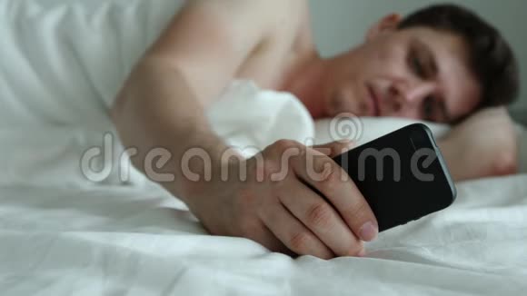 年轻人躺在床上用电话视频的预览图