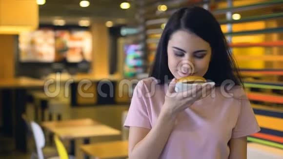 快乐的女人享受美味汉堡的味道在相机上微笑三明治俱乐部视频的预览图