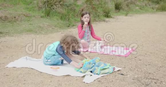 男孩女孩坐在沙滩毛巾上小女孩吃着饼干视频的预览图