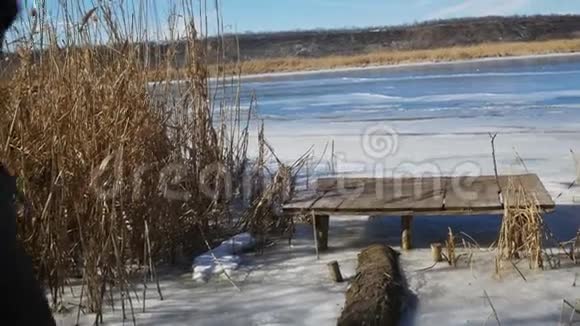 女孩在冰冻的河岸上的木码头上散步享受着大自然的宁静和美丽视频的预览图