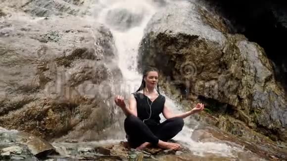 女人在石头上做瑜伽旁边有瀑布视频的预览图