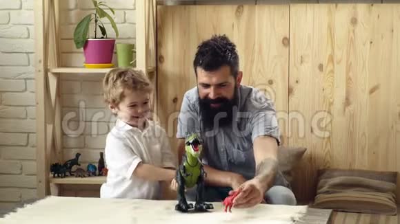 可爱的小孩和长胡子的父亲玩塑料恐龙儿子和父亲之间的战斗视频的预览图