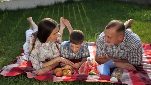 快乐的家庭成员趴在野餐的红毯子上视频的预览图
