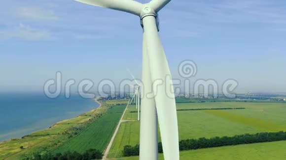 风力涡轮机的空中镜头靠近海面在绿色的田野上视频的预览图