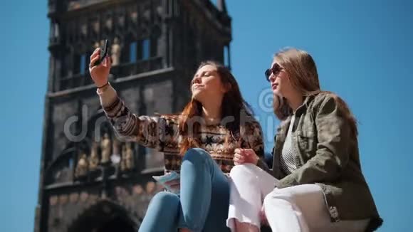 两个女人坐在查尔斯桥塔的背景上自拍视频的预览图