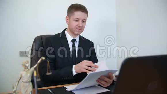 满意的律师在工作桌上阅读纸质文件视频的预览图