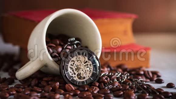时光流逝手表和咖啡种子上的咖啡杯和木桌上的旧书视频的预览图