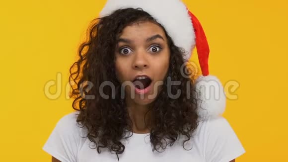 身着圣诞帽的卷发黑发女郎说哇圣诞礼物让人惊讶节日气氛视频的预览图