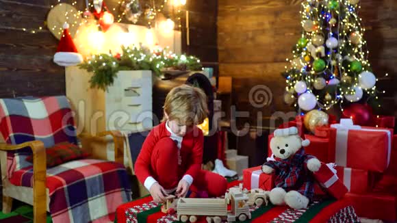 在木屋背景上带圣诞礼物的孩子快乐可爱的孩子打开圣诞礼物祝你快乐视频的预览图