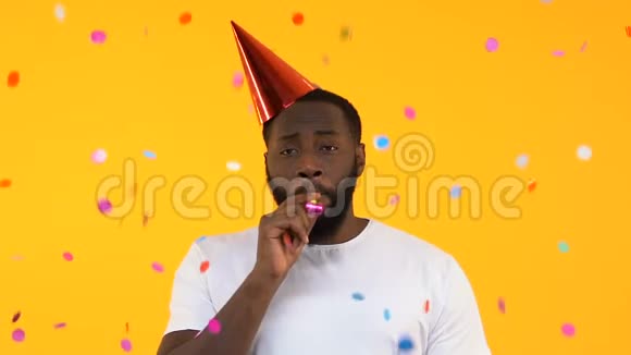 令人不安的非裔美国人戴着派对帽在飘落的纸屑下吹着喇叭视频的预览图