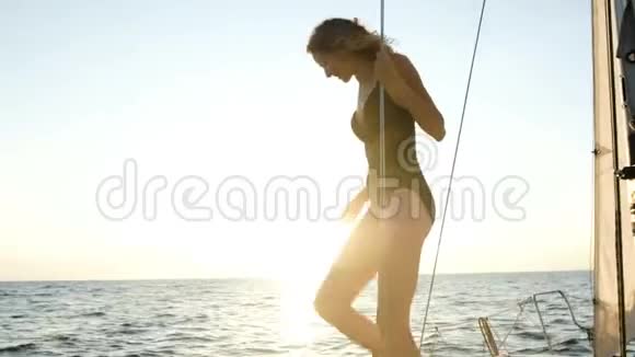 年轻苗条的女孩正准备在日落时分从帆船上跳进公海视频的预览图