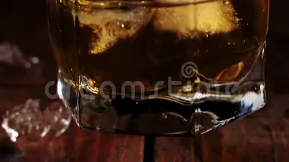 豪华威士忌手从棕色的木桌上拿出一杯带有冰块的金色威士忌准备饮酒视频的预览图