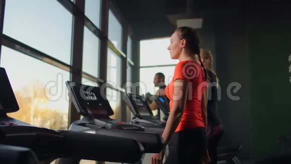一群人走在跑步机上靠近一个大的全景窗口集体有氧运动开始健身课程视频的预览图