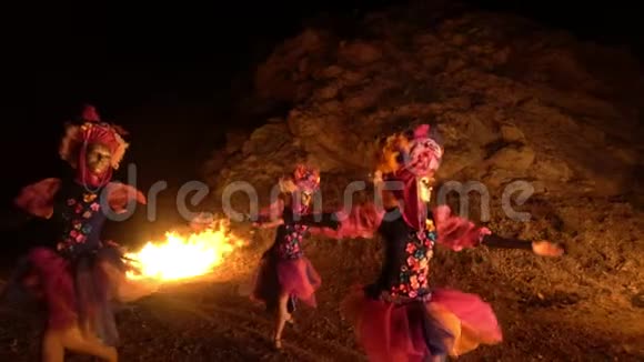三个女孩穿着鲜艳的传统服装和金色面具同时移动双手和旋转他们用火跳舞视频的预览图