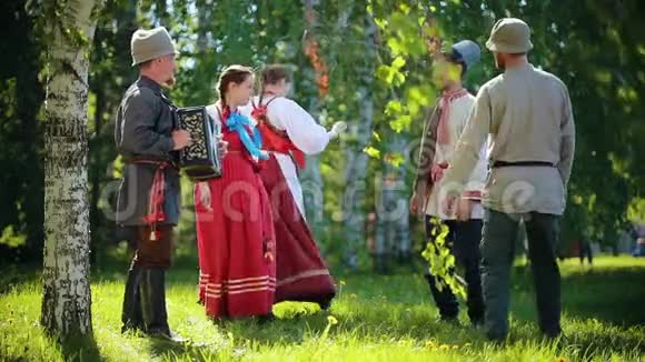 穿着俄罗斯传统服装的人们在球场上跳舞其中一人演奏手风琴音乐视频的预览图