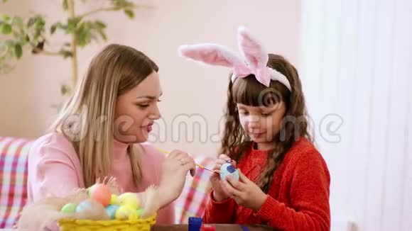 妈妈教她的女儿如何用油漆复活节彩蛋一个有兴趣和一种沉思的味道和颜色视频的预览图