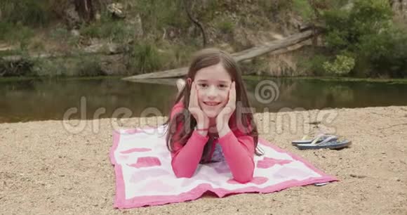 年轻女孩在河滩上晒日光浴时微笑和挥手视频的预览图