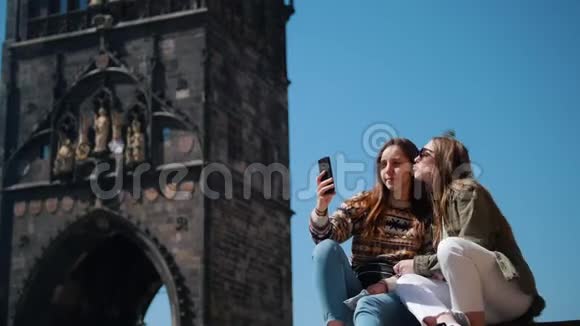 布拉格查尔斯桥桥塔背景上两名妇女坐着自拍视频的预览图