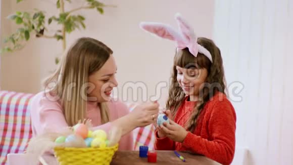 妈妈和女儿用喜悦和微笑装饰一个复活节彩蛋视频的预览图