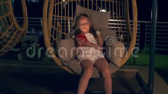 带着智能手机的女孩坐在摇茧椅上视频的预览图