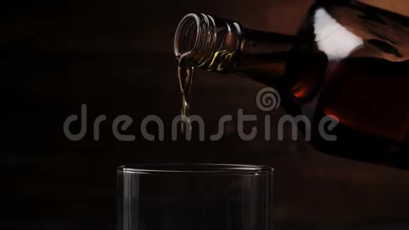 豪华威士忌手把金色的威士忌从一个方形的瓶子倒入一个玻璃杯在桌子上的背景上有真正的冷冰视频的预览图