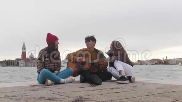 一群年轻的朋友坐在码头边上用吉他唱歌视频的预览图
