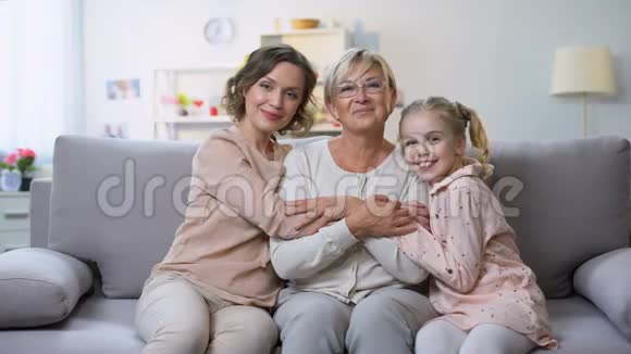 多代女性在家沙发上拥抱微笑相机家庭亲密视频的预览图