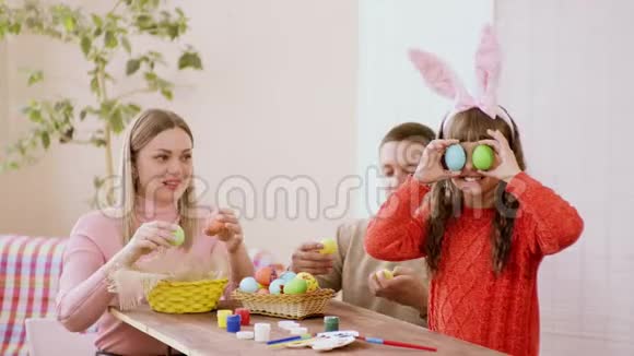 有趣又光彩照人的父母和女儿高加索人出现复活节前玩得开心拿着复活节彩蛋受损视频的预览图