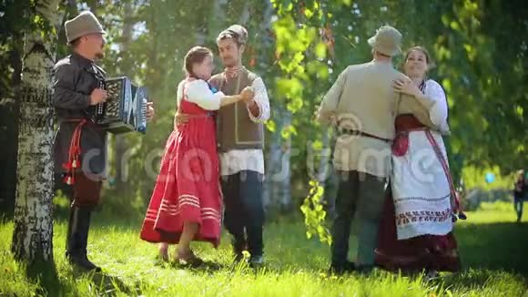 两对身着俄罗斯传统服装的情侣在手风琴音乐的伴奏下在球场上跳舞视频的预览图