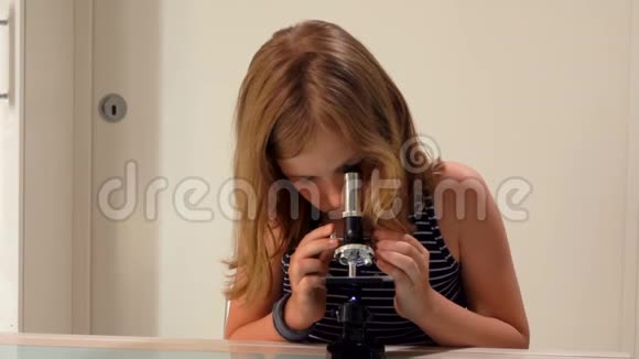 女孩正在显微镜下研究一张幻灯片视频的预览图