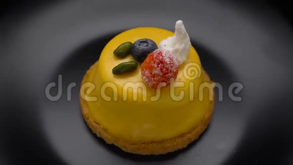 芒果慕斯蛋糕甜点涂上黄色釉料在黑色盘子上旋转视频的预览图