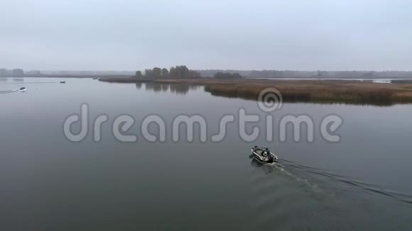 渔夫乘蓝色的船在早晨雾蒙蒙的时候钓鱼渔人用竹子建造的传统房屋视频的预览图