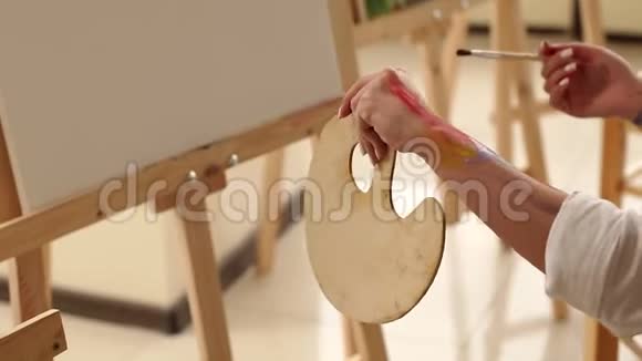 一个艺术家的特写他的手沾满了调色板和画笔的颜料视频的预览图