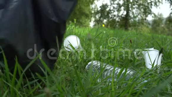 年轻人用灰色的袋子在草地上收集塑料垃圾视频的预览图