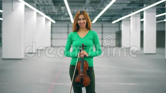 女孩手里拿着小提琴对着照相机微笑视频的预览图