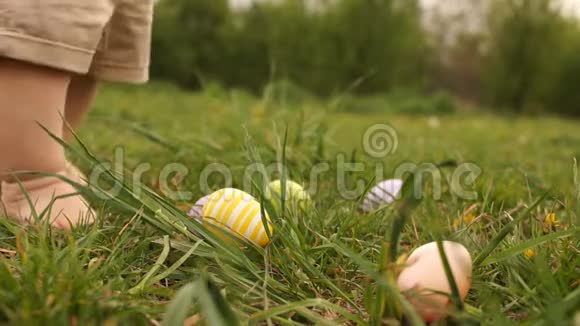 婴儿腿的特写一个孩子正在草地上寻找复活节彩蛋快乐的复活节家庭视频的预览图