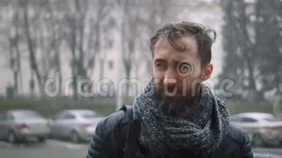 暴风雪中城市里悲伤的年轻胡子男视频的预览图