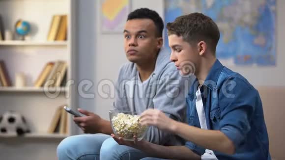 焦虑的多种族朋友吃爆米花和看电视节目闲暇时间视频的预览图