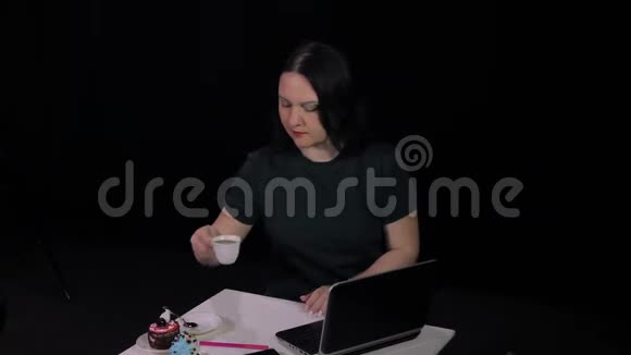 一个女人在咖啡馆的桌子上用电脑敲键盘喝咖啡视频的预览图