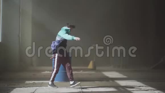 年轻的亚洲嘻哈男舞者穿着蓝色煤气桶前的废弃的黑暗建筑跳舞视频的预览图