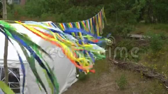 五颜六色的装饰花环挂在派对帐篷附近人们在大自然中散步视频的预览图