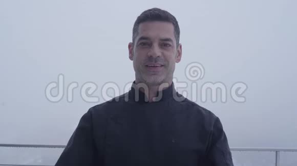 一位满脸笑容的留着胡子身穿黑色制服的厨师的肖像两盘美味的菜肴站在模糊的地上视频的预览图